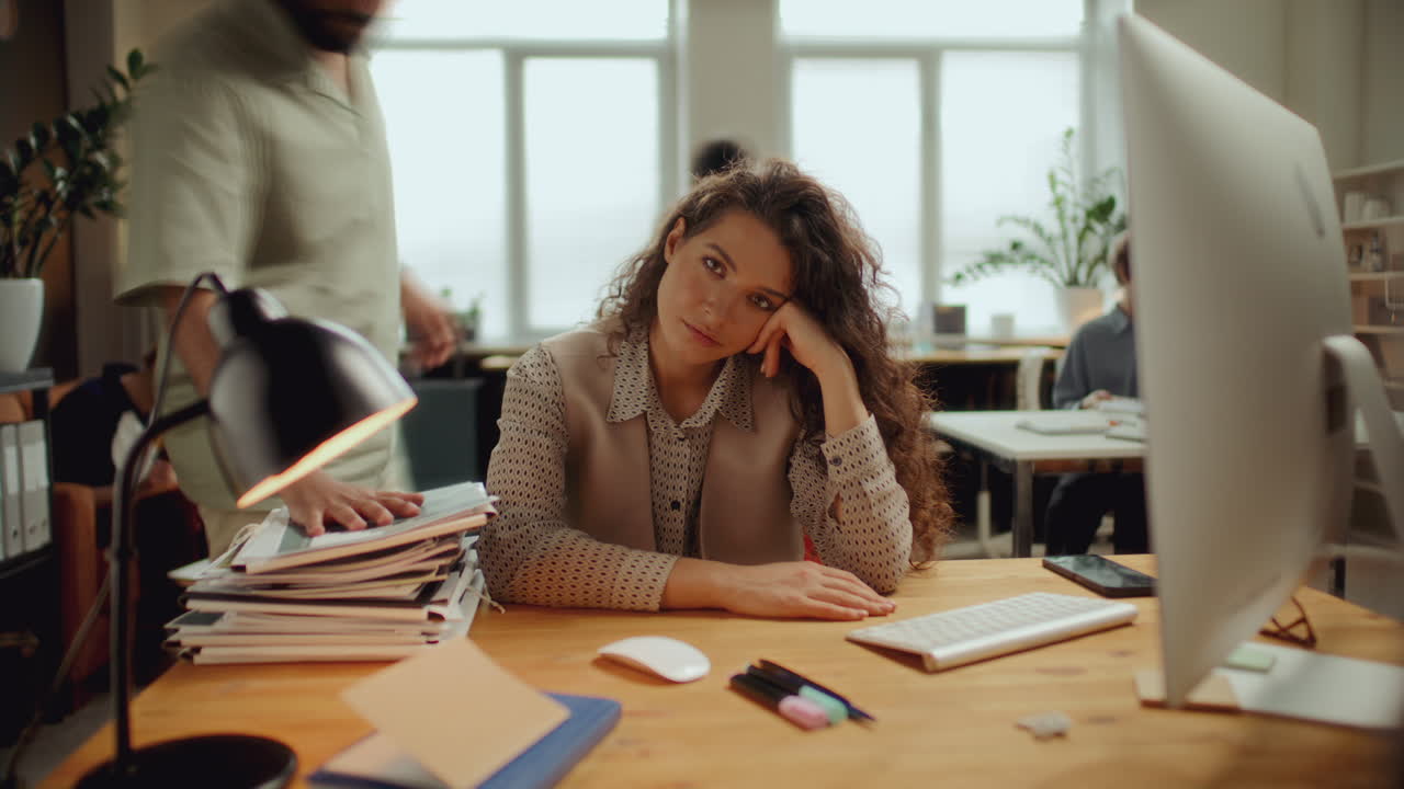 Timelapse di una giovane donna frustrata che riposa la testa sulla scrivania in un ufficio affollato