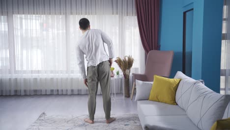 Fitness-instructor-man-warming-up-and-stretching-at-home-with-his-back-turned.