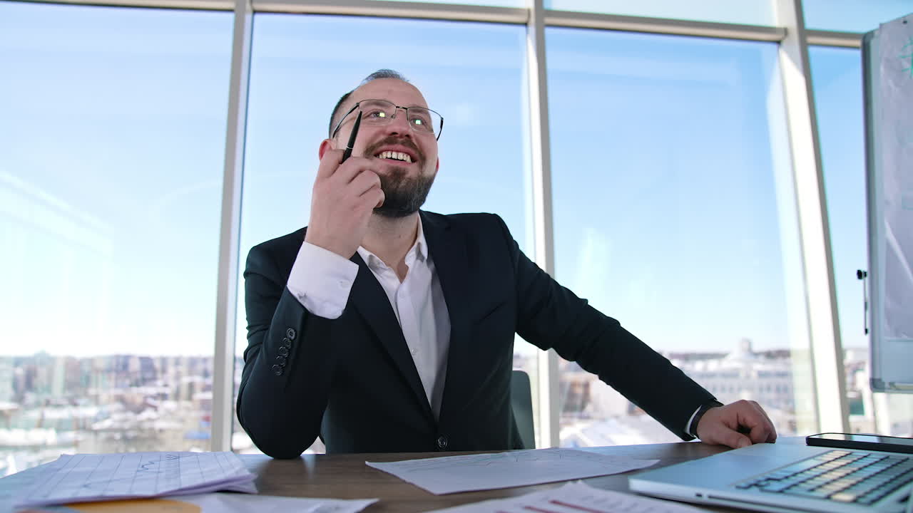 Smiling entrepreneur in office. Portrait of a businessman in glasses sitting at the table with a laptop. Office worker indoors.
