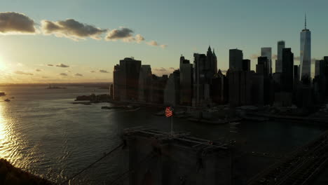 Breath-taking-aerial-footage-of-colourful-sunset-sky-above-water.-Silhouettes-of-Brooklyn-Bridge-and-downtown-skyscrapers.-Manhattan,-New-York-City,-USA