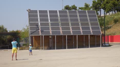 En-La-Ciudad-De-Perea,-Grecia,-El-Padre-Fotografió-A-Su-Hijo-Cerca-De-Paneles-Solares.