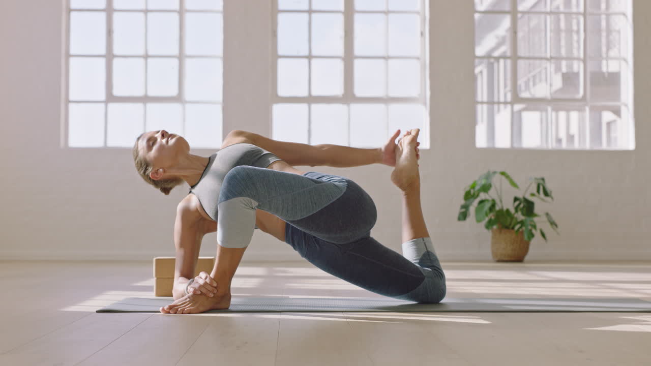 gesunde yoga-frau praktiziert quad-stretch-pose mit niedrigem ausfallschritt und genießt den fitness-lebensstil beim training im studio. schönes körpertraining auf der trainingsmatte bei sonnenaufgang