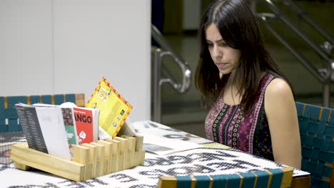 una joven morena seria leyendo un libro sentado en la mesa