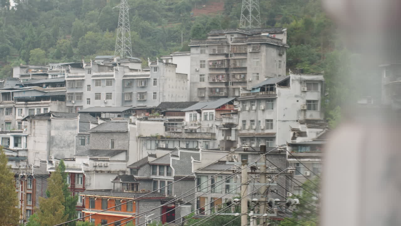 Beton blokların, üst üste yığılmış apartman binalarının otel penceresinden görünümü; ön planda bulanık sütun, kapalı hava ışığı ve puslu arka plan, kentsel yoğunluk ve endüstriyel dokular, kasvetli seyahat görselleri.