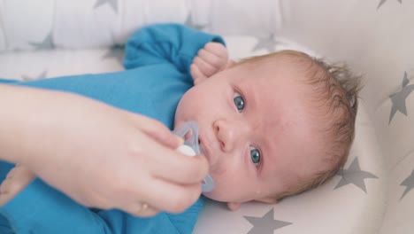 mother takes dummy from little son in star decorated cocoon