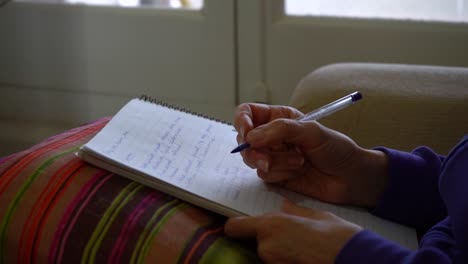 adult female student at home taking notes during online course