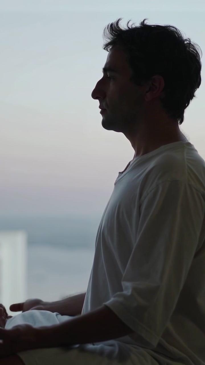 Dawn drawing Middle Eastern man meditating on balcony white shirt holding cloth copy space