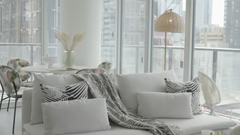 dolly shot of decorated couch and dinning table living and dinning area of a condominium unit during a sunny afternoon