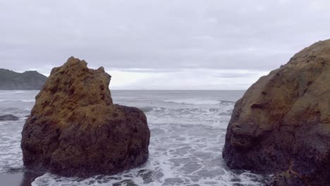 Remote-hidden-beach-on-wild-east-coast-of-New-Zealand-on-cloudy-day,-aerial