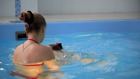 baby in the pool jumping from the side into the water and swims to his mother in slow motion