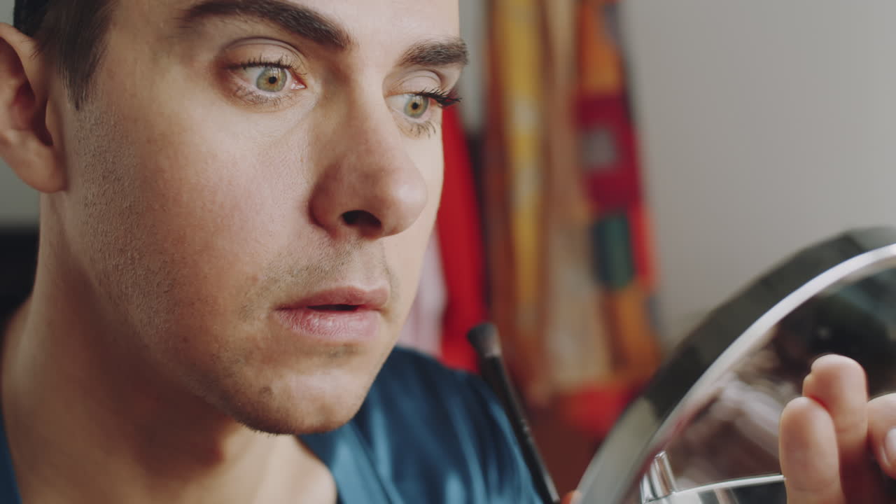 joven hombre transgénero aplicando sombra de ojos con un pincel