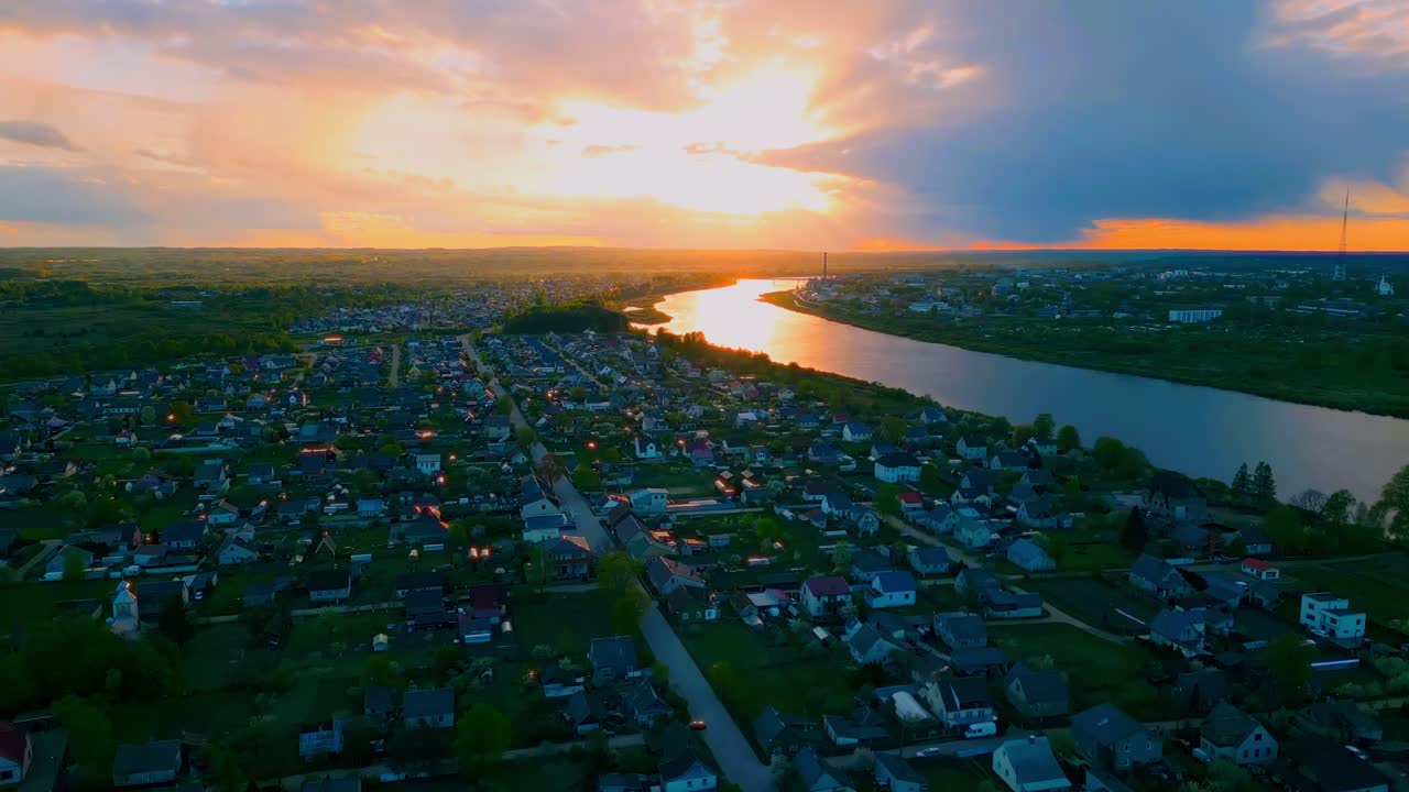Aerial view at sunset over a suburban area in Daugavpils with a river reflecting golden light and dense rooftops. Location: Daugavpils, Latvia (Daugavpils, Latvija)
