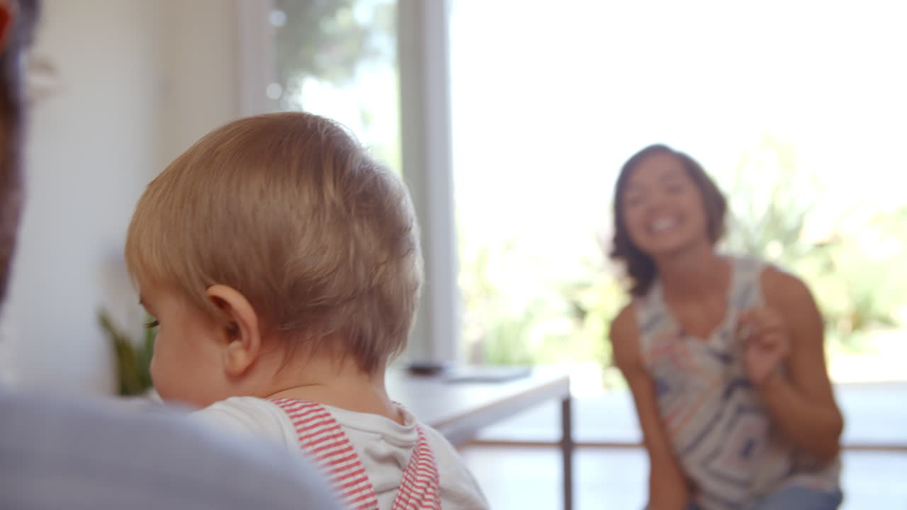 부모 는 아기 아들 이 집 에서 첫 단계 를  ⁇ 는 것 을 지켜보고 있다