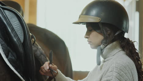 woman fastening straps of saddle on horse
