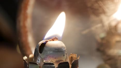 close up of man lighting an old fashioned lamp using matches