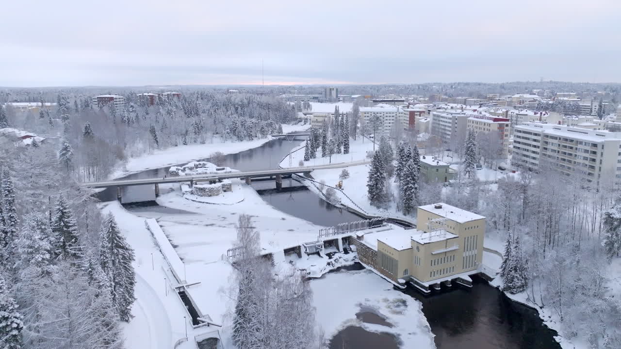 Aerial ascending shot in front of the snowy Ammakoski dam and the Kajaani Castle