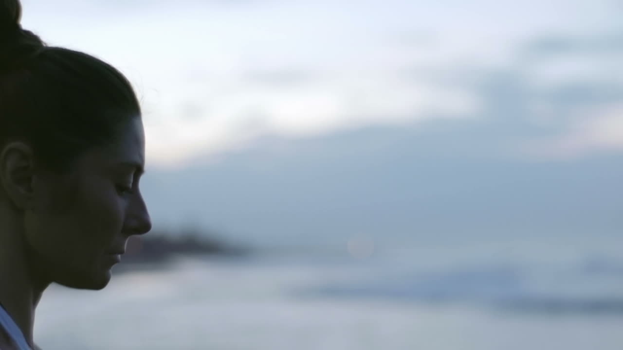 해변에서 요가를 하는 젊은 여성의 얼굴에 초점을 맞춘 카메라