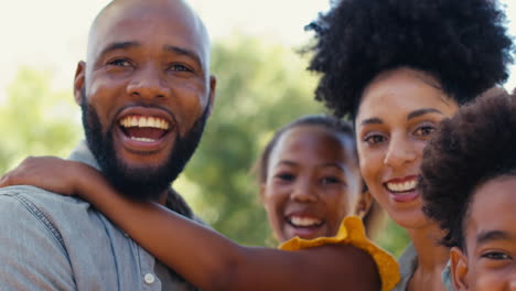 Close-Up-Portrait-Of-Smiling-Family-Standing-In-Summer-Garden-Or-Countryside-Smiling-At-Camera