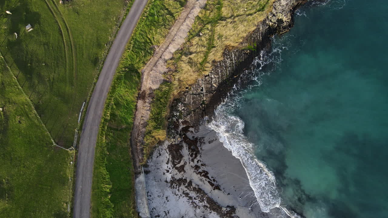 las olas del océano golpean la costa y una pequeña playa en la costa oeste de irlanda