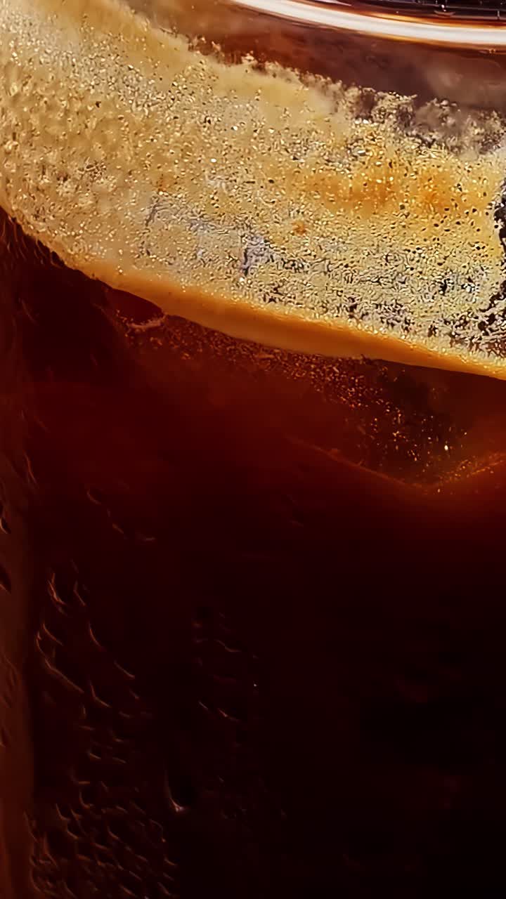 Primo piano della schiuma di crema densa e testurizzata sopra un caffè freddo in un bicchiere