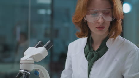 portrait-of-female-lab-technician-in-clinic-of-curing-covid-19-expert-is-working-with-microscope-for-research-virus-in-analysis-of-people