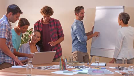 Equipo-De-Negocios-Creativo-Trabajando-En-Una-Computadora-Portátil-Mientras-Sus-Colegas-Miran-La-Pizarra