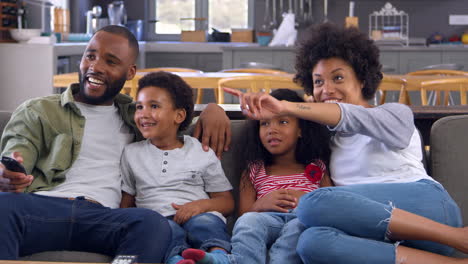 Familie-Sitzt-Auf-Dem-Sofa-Im-Offenen-Wohnzimmer-Und-Schaut-Fern