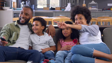 familia sentada en el sofá en una sala de estar abierta viendo televisión
