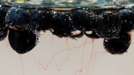 red juice flows out of the blueberry in the cider, slow movement, blurred