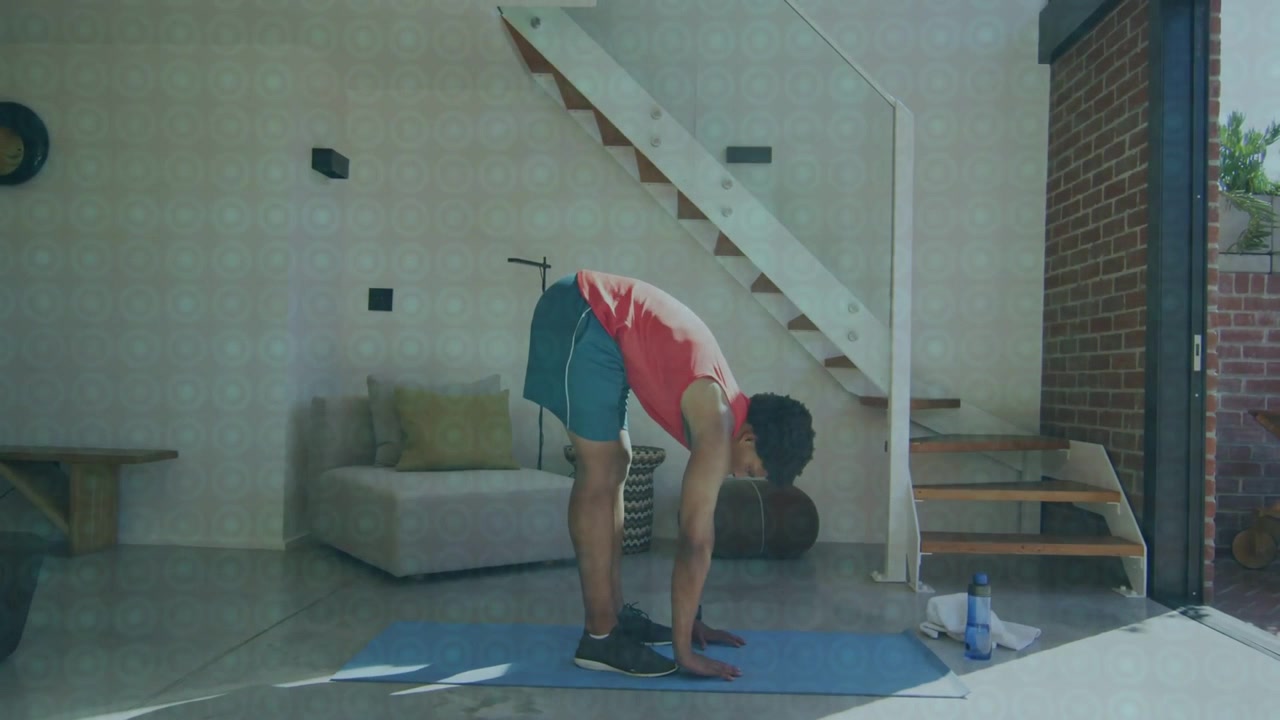 Vertical video: Starting hip hinge man in red tank folding forward, stretching on blue mat at home