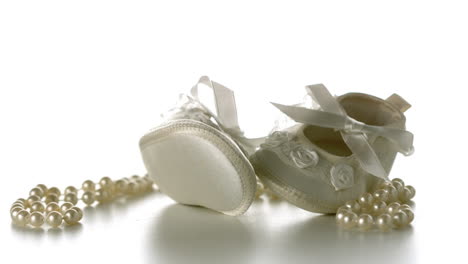 baby shoes falling onto string of pearls