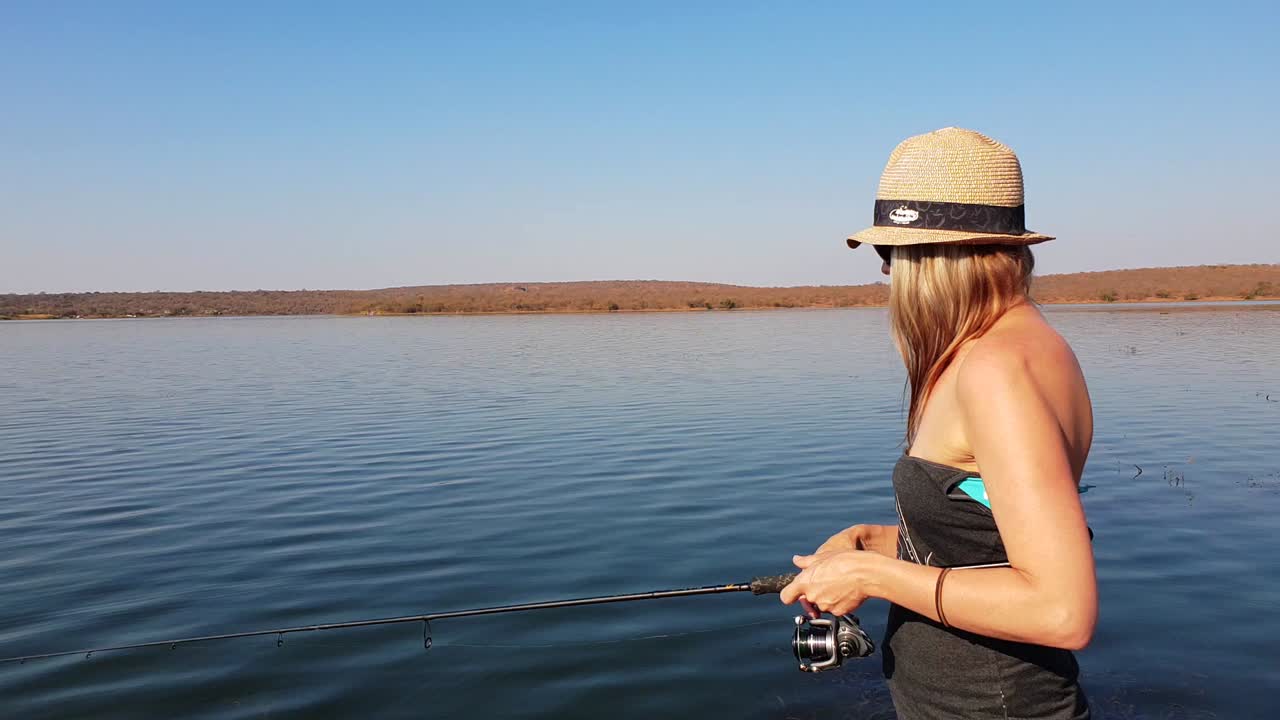 hermosa chica pescando lubina desde un bote en un día soleado en áfrica