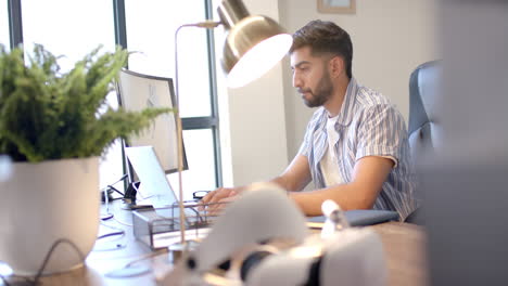 working in modern office, man using laptop with vr headset on desk