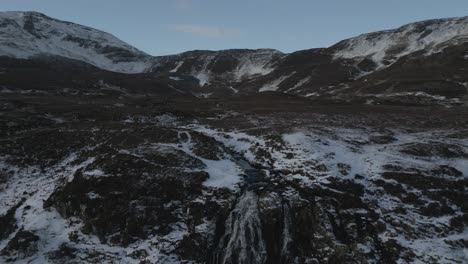 Toma-Aérea-De-Montañas-Cubiertas-De-Nieve-Y-Cascada-Del-Velo-De-La-Novia-En-Skye,-Escocia