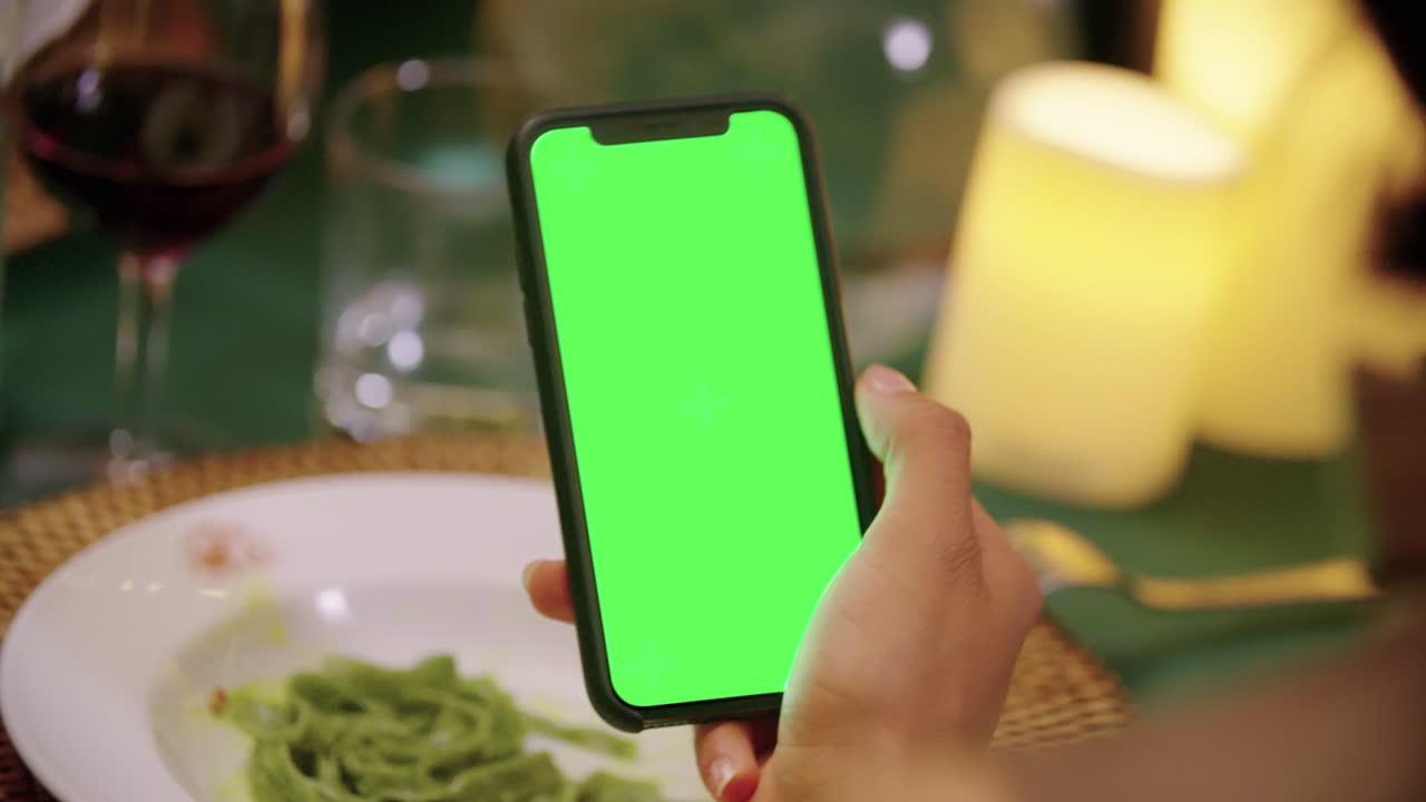 mujer usando un dispositivo de teléfono inteligente de pantalla verde durante una elegante cena de noche gourmet. amigos viaje italiano en umbria.4k cámara lenta