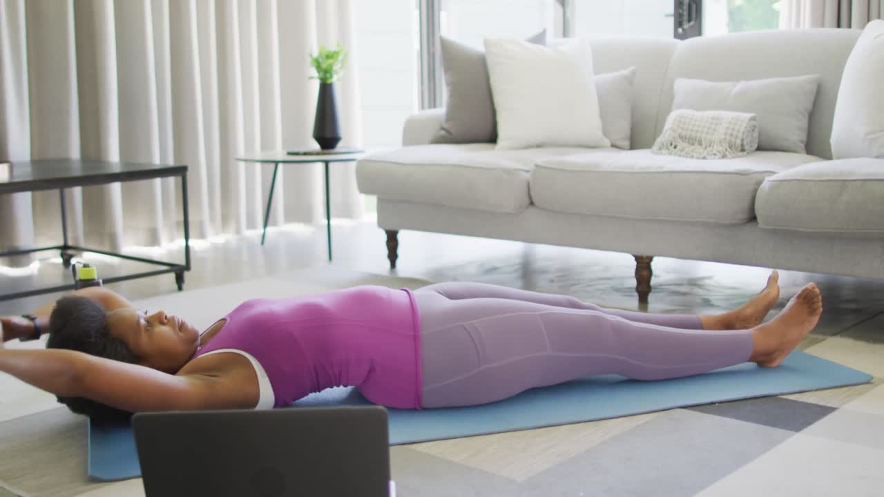 feliz afroamericano usando ropa deportiva, haciendo ejercicio, usando una computadora portátil