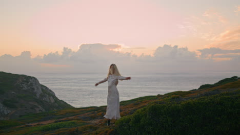 dress model turning sunset valley. cute woman spinning enjoying ocean cliff