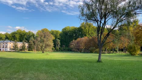 panoramic filming in the beautiful surroundings of the casa del labrador in the prince's gardens, we see a green field, a large grove of trees and the country residence of the former kings.