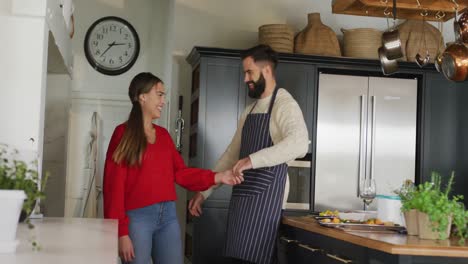 video of happy caucasian couple peeling vegetables in the kitchen