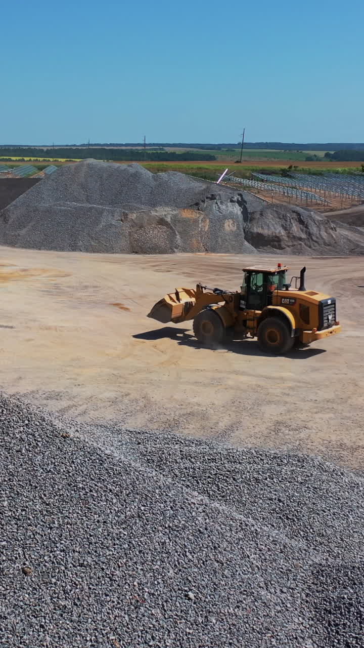 Bulldozer at construction site. Aerial view of heavy earthmover working at construction site Vertical video