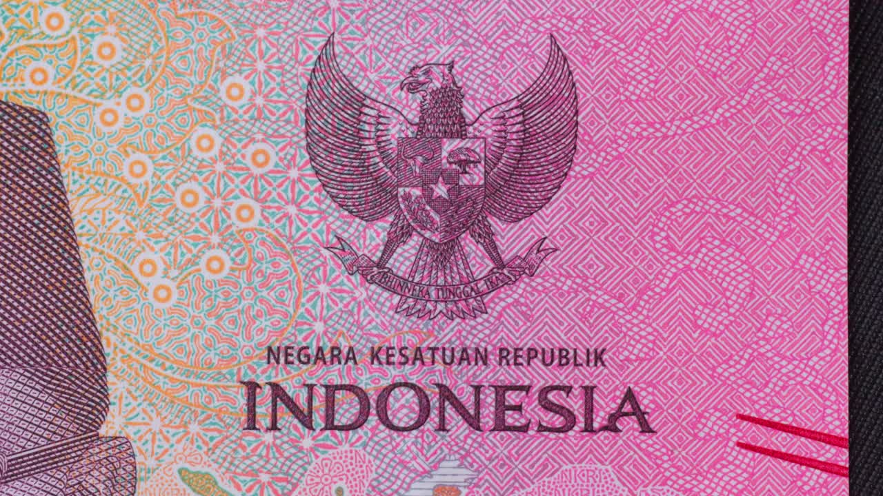 Close-up of Indonesian Rupiah, panning across bill to reveal the Garuda, then portraits of Soekarno and Mohammad Hatta