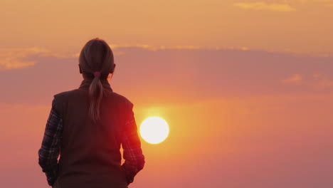 Silhouette-Einer-Frau-Mittleren-Alters,-Die-In-Die-Untergehende-Rote-Sonne-Geht