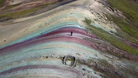antena, órbita, drone disparó alrededor de un hombre caminando por la montaña del arco iris palcoyo, en valle rojo, o valle rojo, montañas de los andes, día soleado, en perú, sudamérica