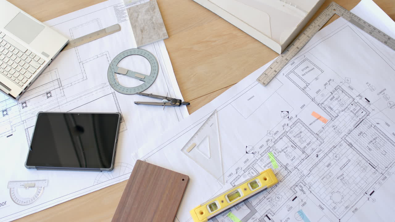 Planning construction project, architectural blueprints with tablet, compass, and level on desk