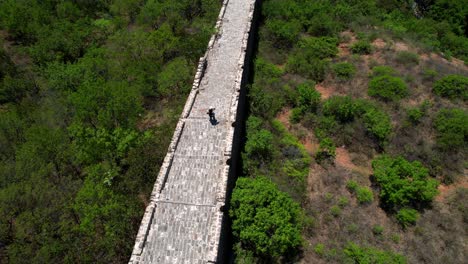 aerial top down view of solitaire woman standing on top of the great wall of china at noon in jinshanling section.
