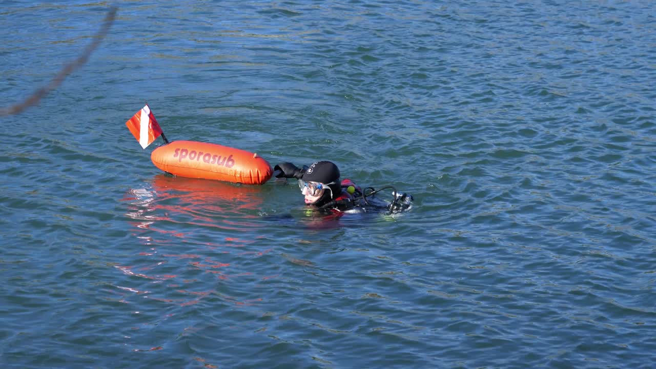 un buzo nada mar adentro con su boya de rescate roja