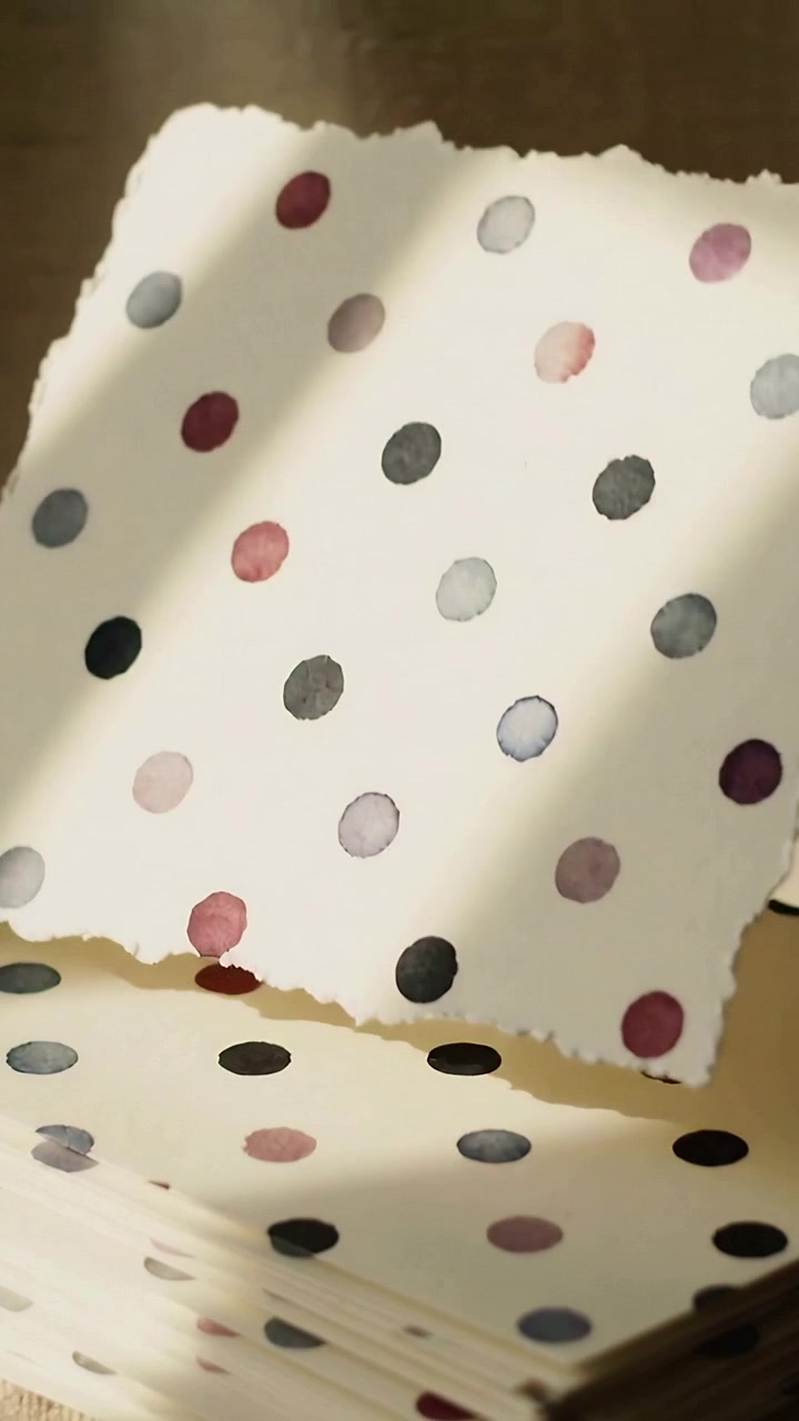 Vertical video: Shifting camera nudging loose sheet from dotted stack on table, with slatted light