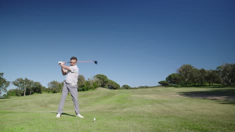 A golfer swinging on a green golf course