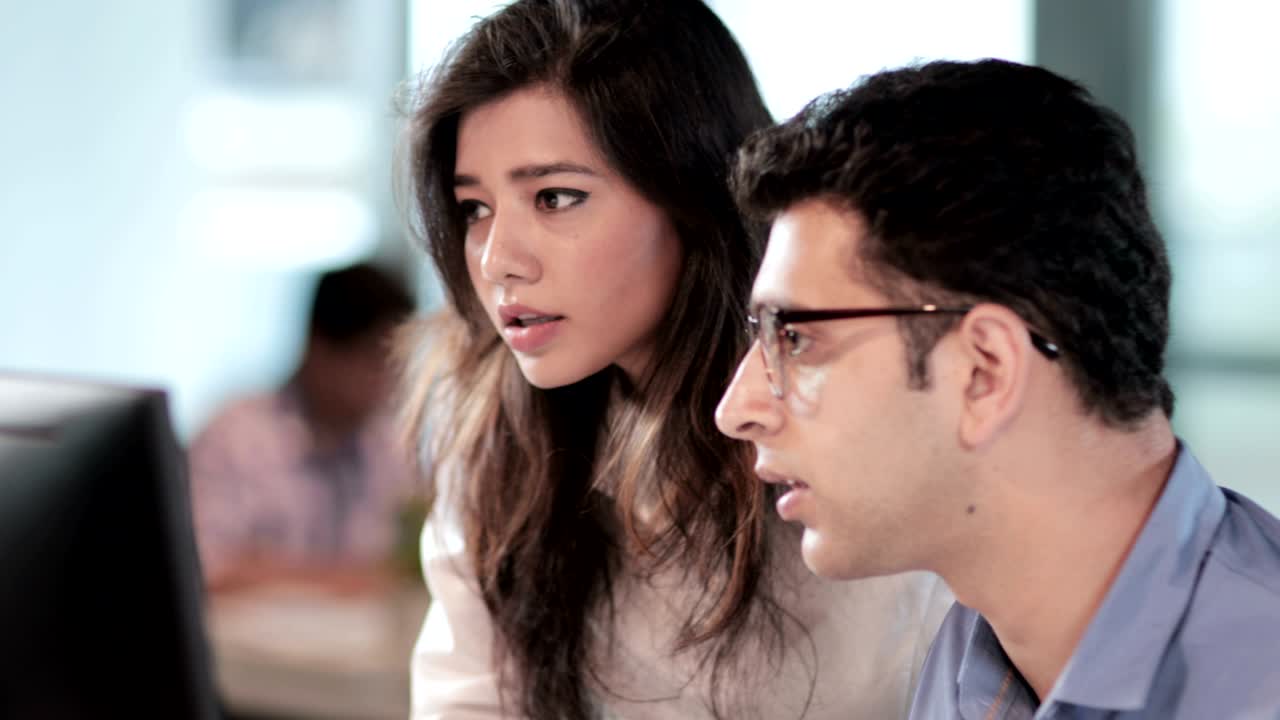 A focused and attractive male and female associates working on a important business project before deadline.
