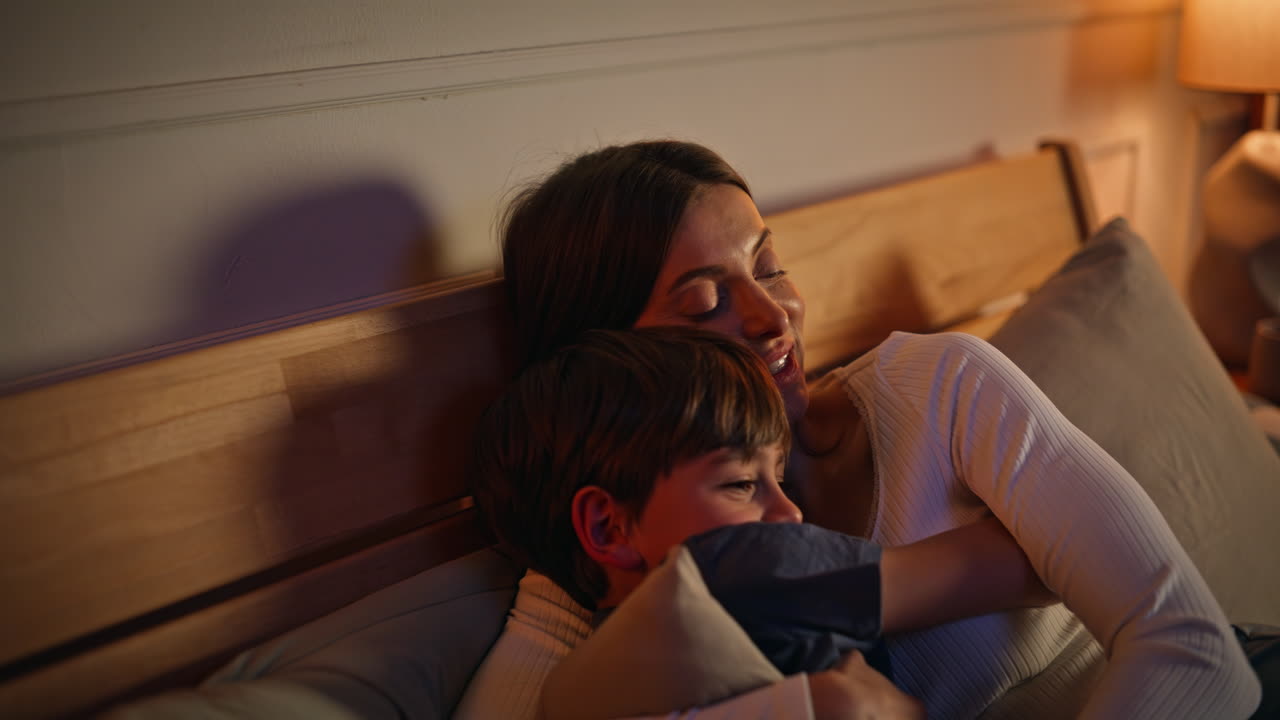 Mommy son hugging evening enjoying bedtime routine closeup. Smiling woman boy
